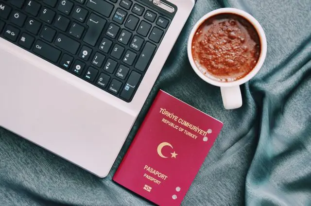 Seyahat planlaması için Türk pasaportu, laptop ve kahve ile çalışma masası